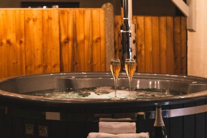 The private wood-fired hot tub and two glasses of champagne at Pilgrim Cottage, Cheshire
