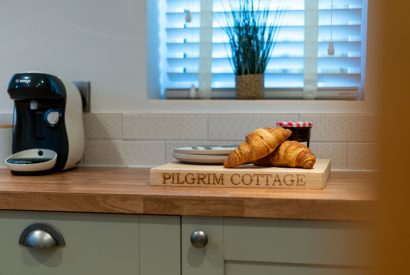 The kitchen counter with a coffee machine and croissants on the chopping board at Pilgrim Cottage, Cheshire
