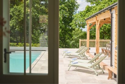 The swimming pool and sun loungers at Olive Tree Cottage, Sussex