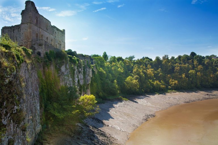 Castle ruins on a cliff side overlooking water in Chepstow