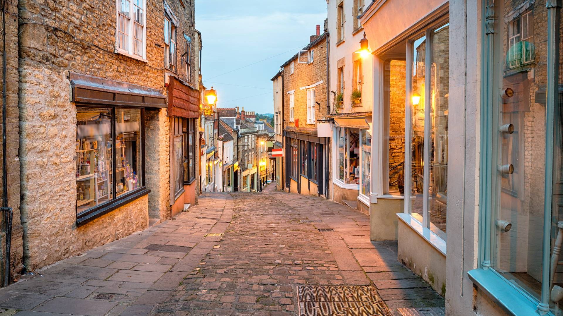 A narrow street of shops in Frome at dusk