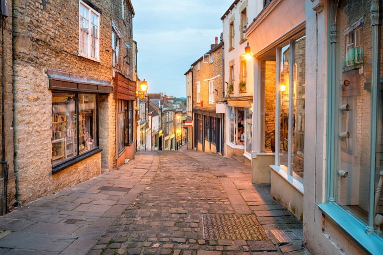A narrow street of shops in Frome at dusk
