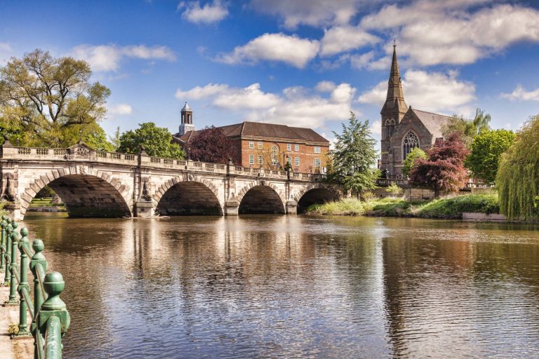 A river with a bridge in front of a church in Shrewsbury