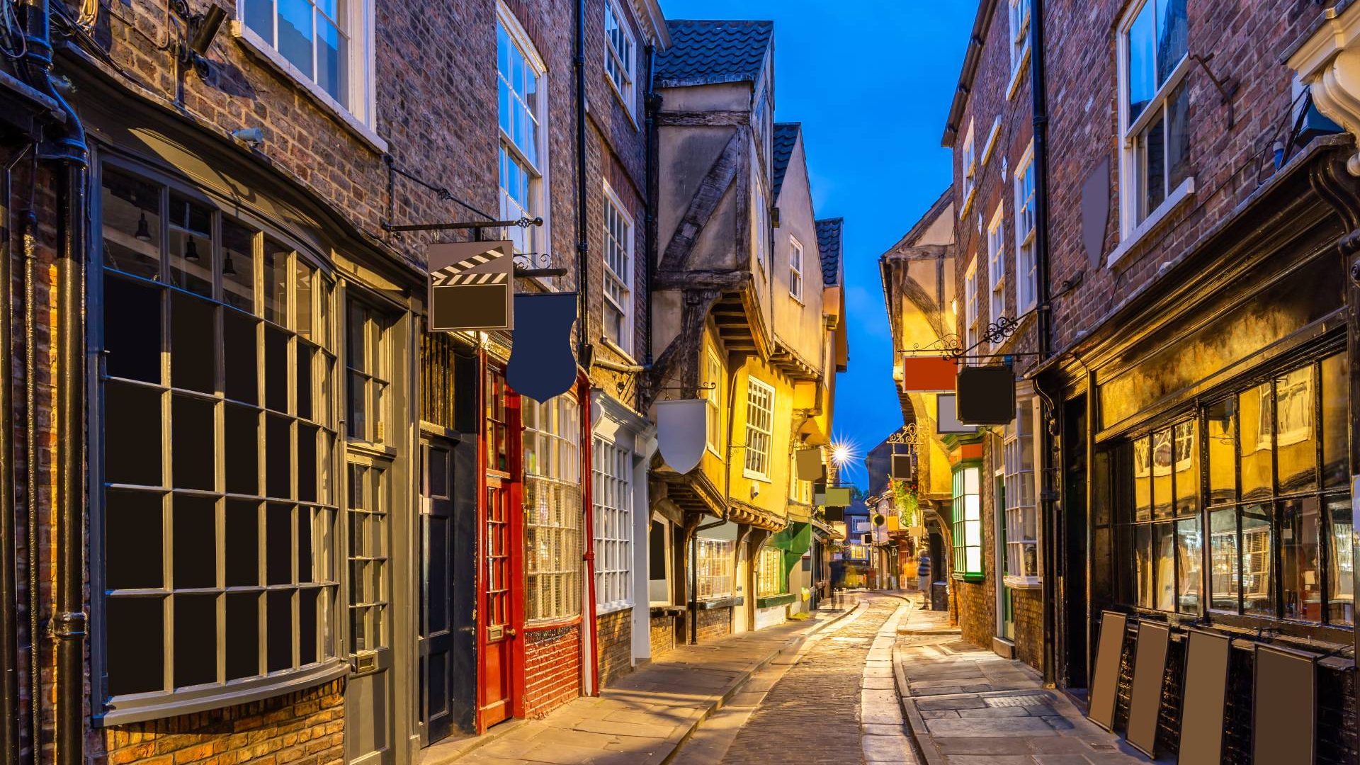 A narrow road lined with shops in the city of York at night