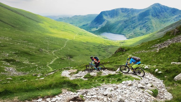 two people mountain biking down a hill in the Lake district