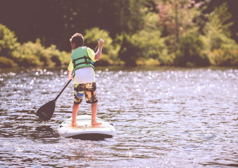 Young boy standing on paddle board in a lake on a summer day