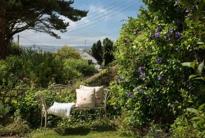 A bench at the end of the garden overlooking the countryside at Hempston Cottage, Devon