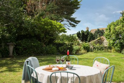 The lawned garden with an outdoor dining table at Hempston Cottage, Devon
