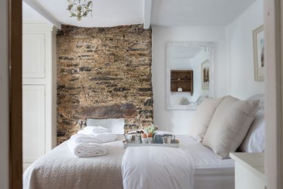 A double bedroom with exposed stone wall feature at Hempston Cottage, Devon