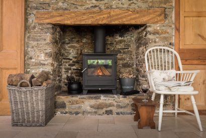 A stone fireplace with a log burner at Hempston Cottage, Devon