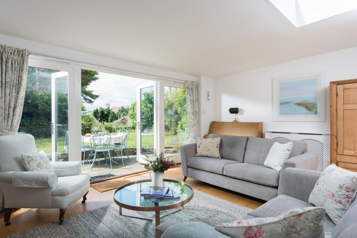 The living room with doors leading to the patio and garden at Hempston Cottage, Devon