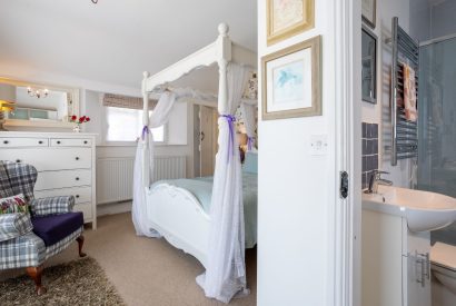 An ensuite bedroom with a four-poster bed at Sweet Shop Cottage, Somerset