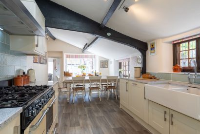 The galley kitchen with a large dining table at Sweet Shop Cottage, Somerset