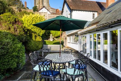 The patio with a dining table at parasol at Thatch Corner, Somerset
