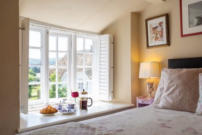 A single bedroom with a window seat overlooking the garden at Thatch Corner, Somerset