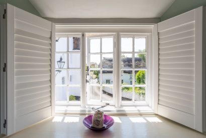 A window with shutters overlooking the quaint village at Thatch Corner, Somerset