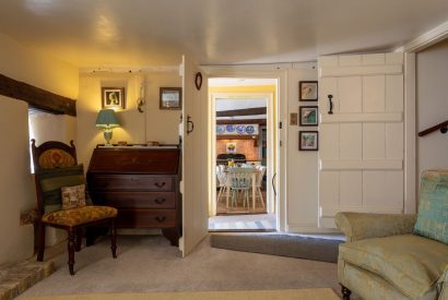 The living room with a writing desk leading to the dining room at Thatch Corner, Somerset