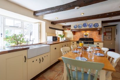 The kitchen with a large dining table at the centre at Thatch Corner, Somerset
