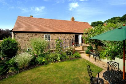 The garden with a dining table overlooking the exterior of Exmoor Barn, Somerset