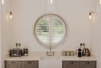 The kitchen with a circular window overlooking the garden at Brickworks and Vines, Isle of Wight