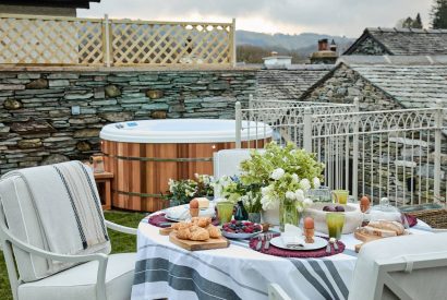 The outdoor dining table and hot tub at Beatrix Cottage, Lake District