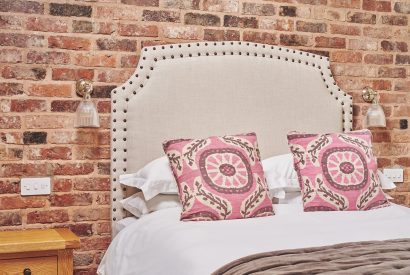 The king-size bed against the exposed brick wall at The Dairy Barn, Worcestershire 