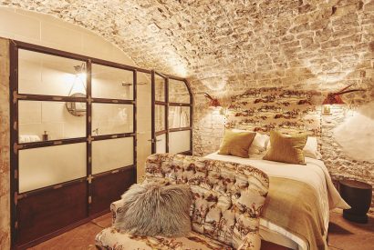 The king-size bedroom with exposed brick walls at Fritillaria Cottage, Vale of Glamorgan