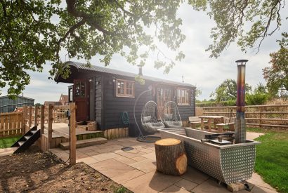 The exterior of the shepherd's hut with the wood-fired Swedish Hikki hot tub at The Hangout Hut, Worcestershire 