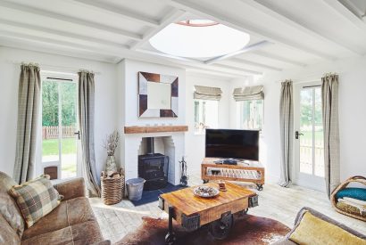 The living room with a log burner and views over the garden at Osborne Lodge, Herefordshire