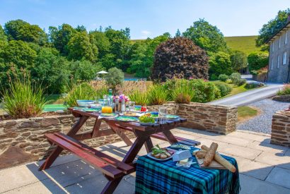 The patio area with a picnic bench overlooking the countryside at Dart Cottage, Devon