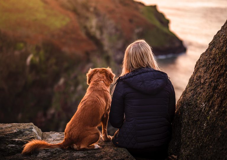 A young girl and her dog watch the sunset at The Valley of the Rocks