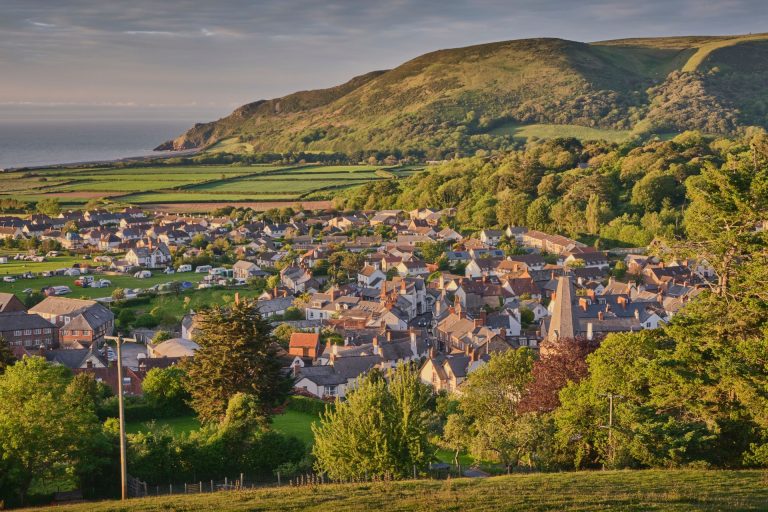 View down on the village of Porlock in Exmoor with a church steeple in view and the sea in the distance