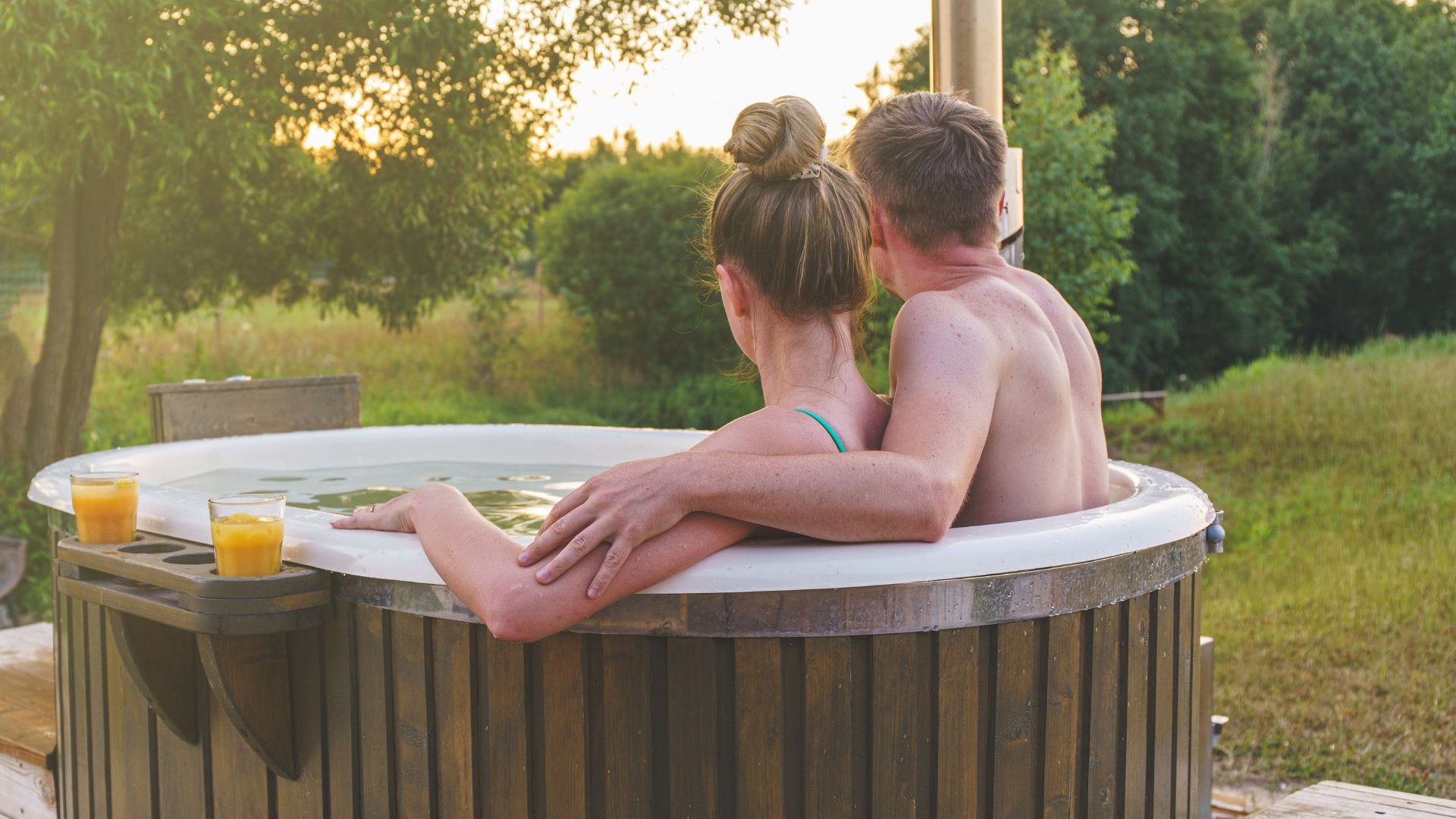 Young couple in an outdoor hot tub gazing at the countryside scenery