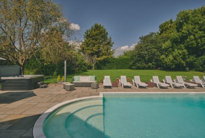 Sun loungers overlooking the swimming pool and hot tub at Sharnbrook Retreat, Bedfordshire