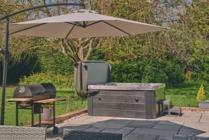 The outdoor entertaining space with a hot tub and barbeque at Sharnbrook Retreat, Bedfordshire