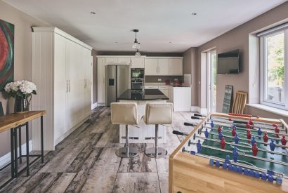 The open-plan kitchen with an island with bar stools and a foosball table at Sharnbrook Retreat, Bedfordshire