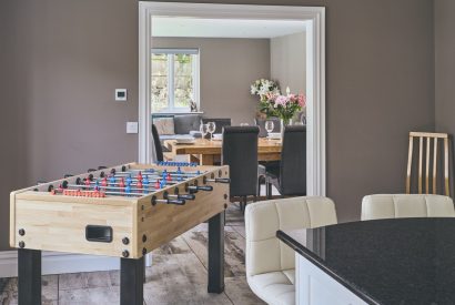 The open-plan kitchen with a foosball table leading towards the dining room at Sharnbrook Retreat, Bedfordshire