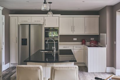The kitchen with an island and two bar stools at Sharnbrook Retreat, Bedfordshire
