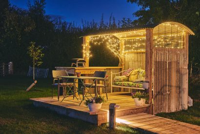 The outdoor lounge at night with a two-seater table and day bed at night at Windmill Old Orchard, Somerset