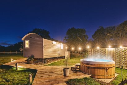 The side of the shepherd's hut and outdoor lounge at night at Windmill Old Orchard, Somerset
