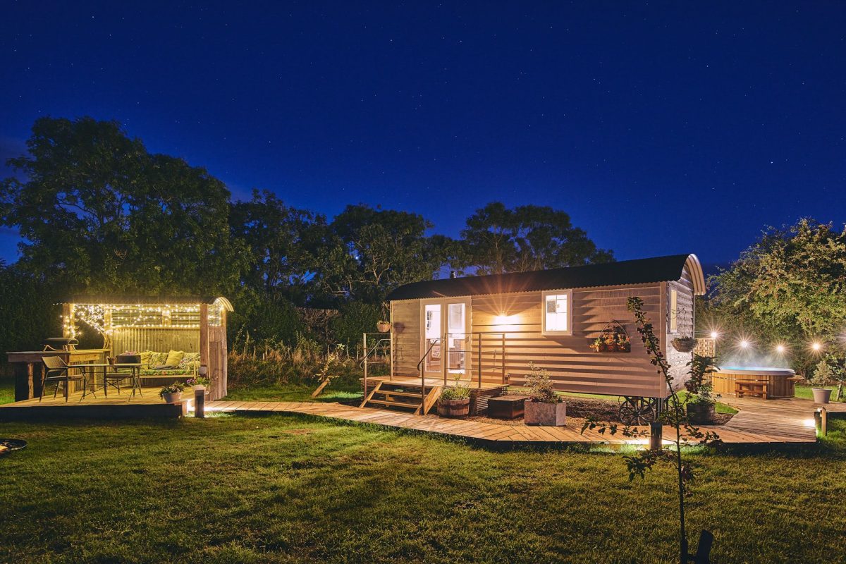 The exterior of the shepherd's hut and outdoor lounge at night at Windmill Old Orchard, Somerset