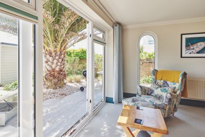 A living room with doors to the garden at Beach Manor, West Sussex