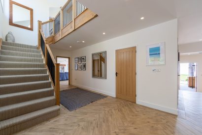 The entrance hall with an oak staircase leading to the living room at Minack View, Cornwall