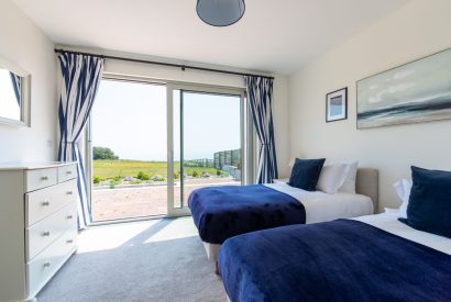 A twin, ground floor bedroom with doors onto the patio at Minack View, Cornwall