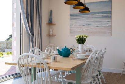 A dining table overlooking the garden and sea view at Minack View, Cornwall