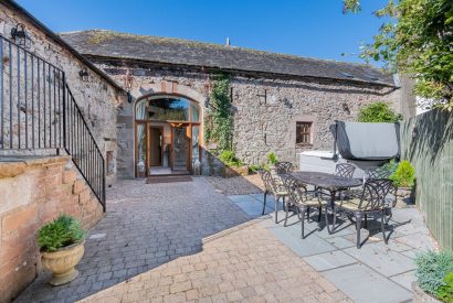 The private patio with a hot tub and a dining table and chairs at Rose Walls, Lake District 