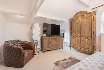 A single armchair and smart TV in a king-size bedroom at Rose Walls, Lake District 