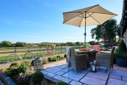 The outdoor rattan table and chairs with countryside views at Stable Barn, Cotswolds 