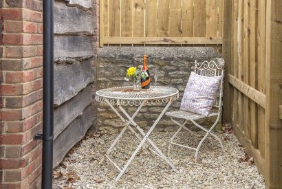 A table and chair in the courtyard at Little Calf Cottage, Wiltshire