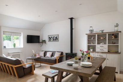 The open plan living room and dining room with a log burner at Farmyard Cottage, Wiltshire